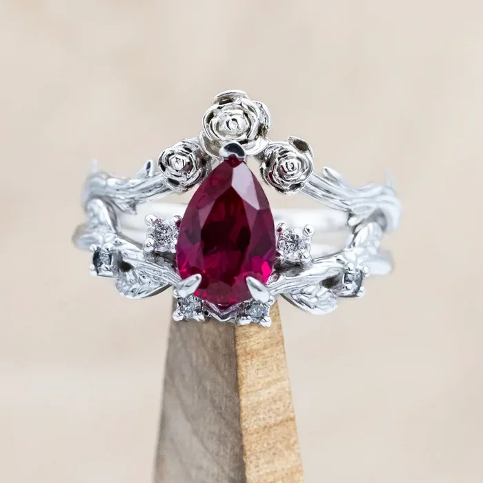 “HARLOW” – PEAR CUT LAB-GROWN RUBY WOMEN’S ENGAGEMENT RING WITH SALT & PEPPER DIAMOND ACCENTS, BRANCH-STYLE BAND & TRACER