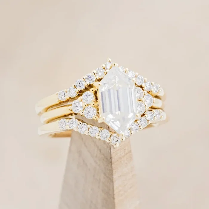 “OCTAVIA” – BRIDAL SUITE – ELONGATED HEXAGON CUT MOISSANITE ENGAGEMENT RING WITH DIAMOND ACCENTS & “LAYLA” TRACERS